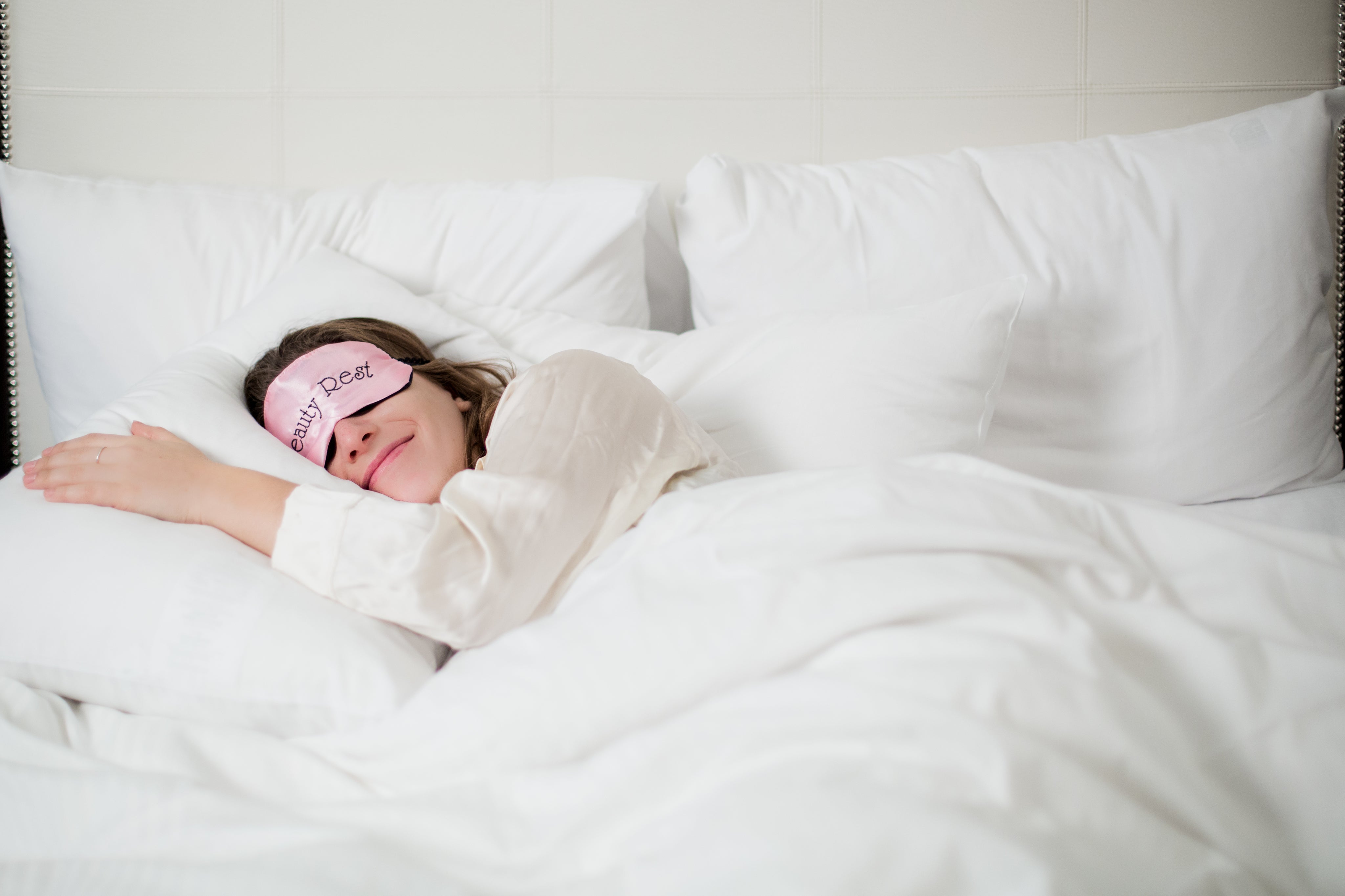 Frau schläft ruhig und erholsam in einem weißen Bett