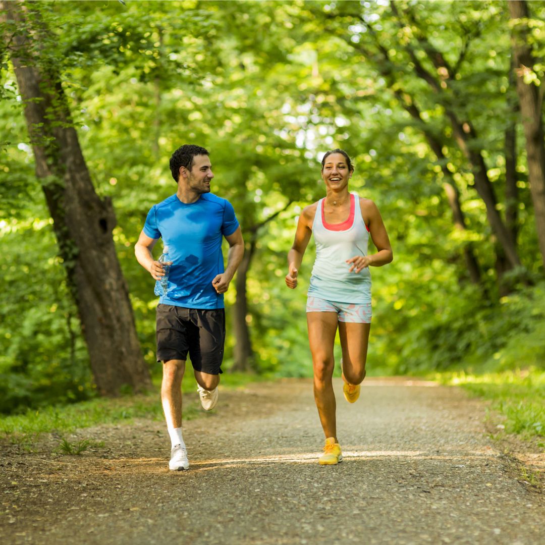 Ein Mann und eine Frau joggen im Wald.